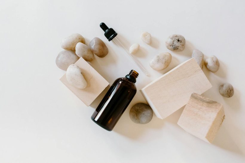 Flat lay of essential oil bottle with stones and wooden blocks, perfect for wellness themes.