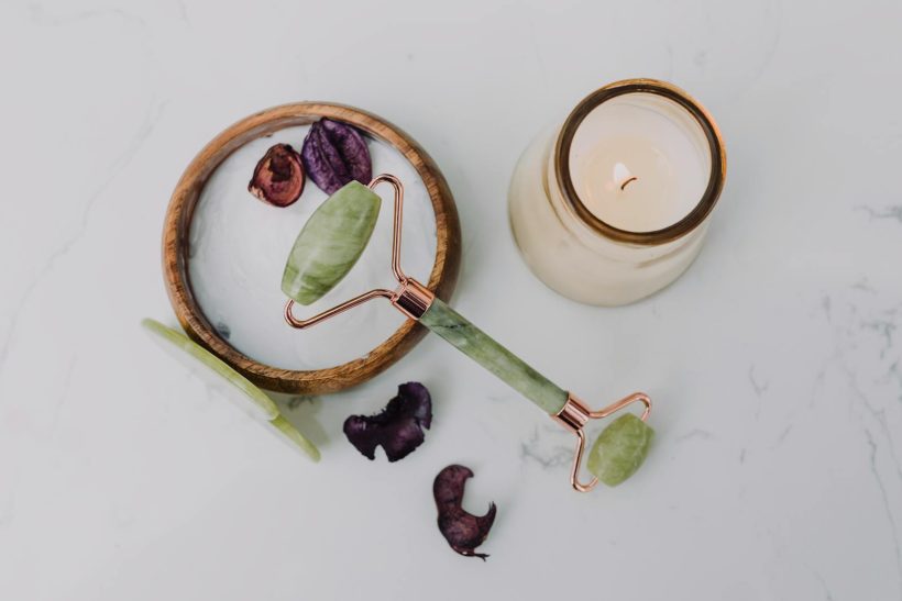 A relaxing flat lay of a jade roller and candle, perfect for a spa day at home.